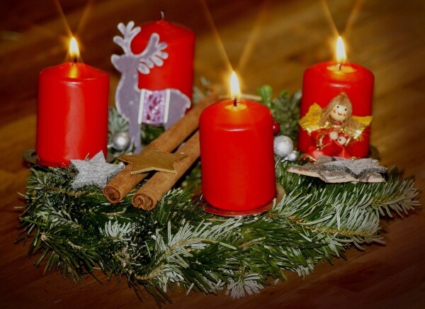 Echter Adventskranz Rot mit brennender Kerze.